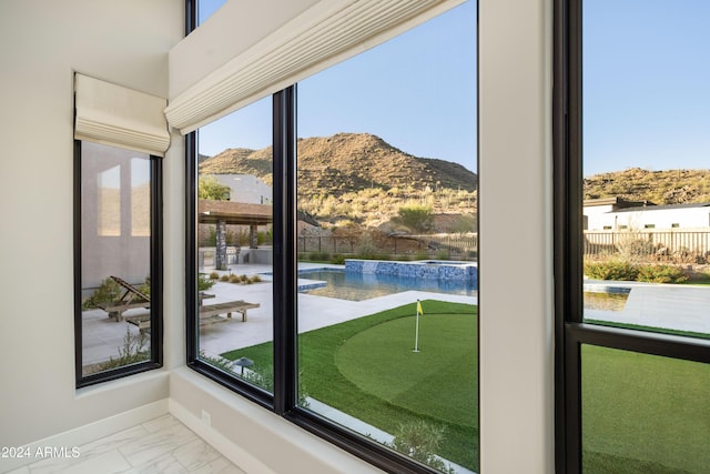 interior space featuring marble finish floor, a mountain view, and baseboards