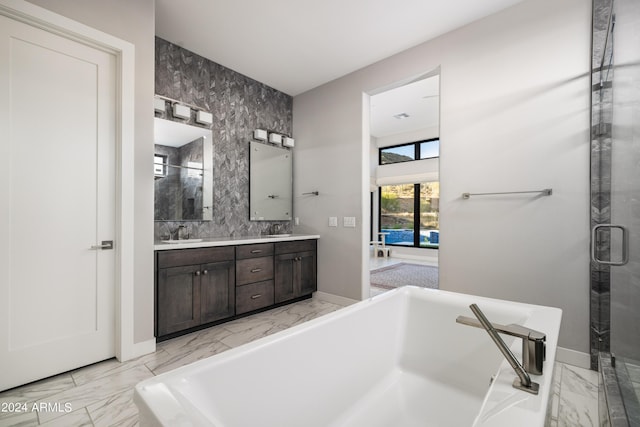 bathroom with double vanity, marble finish floor, a sink, and a soaking tub