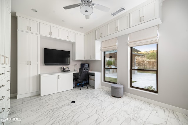 home office with a ceiling fan, visible vents, baseboards, marble finish floor, and built in desk