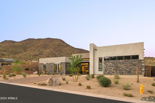 southwest-style home featuring stone siding, a mountain view, and stucco siding