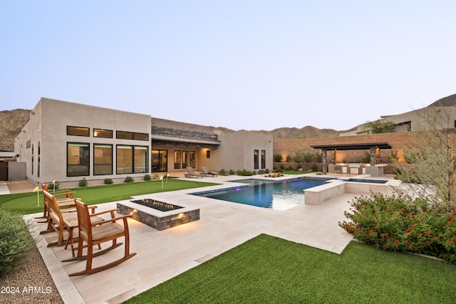 back of house featuring a patio, stucco siding, a hot tub, an outdoor pool, and a fire pit