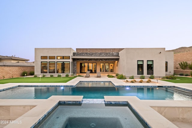 rear view of house with a pool with connected hot tub, a patio, and stucco siding