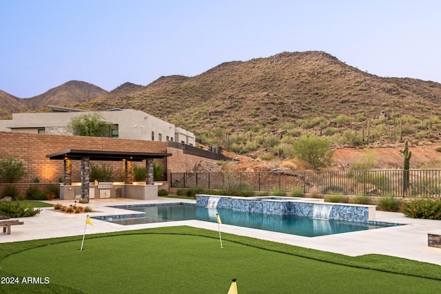 view of pool featuring a patio area, a fenced backyard, a mountain view, and exterior kitchen