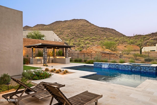 view of pool with an outdoor kitchen, a fenced backyard, a mountain view, an in ground hot tub, and a fenced in pool