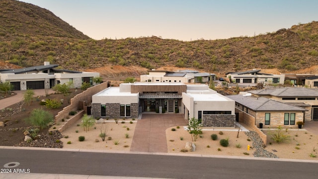 view of front of home with stone siding, a mountain view, and stucco siding