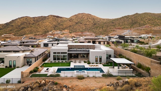 rear view of property featuring a mountain view, a fenced backyard, a patio, and stucco siding