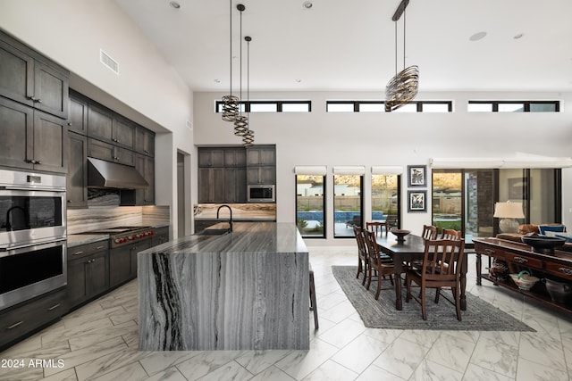 kitchen featuring under cabinet range hood, stainless steel appliances, visible vents, marble finish floor, and dark stone countertops