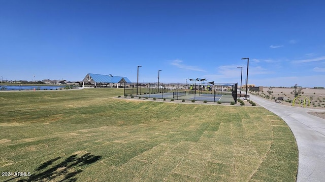 surrounding community featuring a water view, a lawn, and tennis court