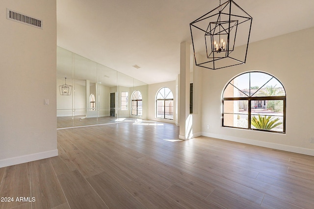 unfurnished living room featuring light wood-type flooring, an inviting chandelier, and a towering ceiling