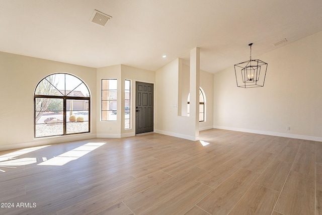 interior space with light hardwood / wood-style flooring, lofted ceiling, and a notable chandelier