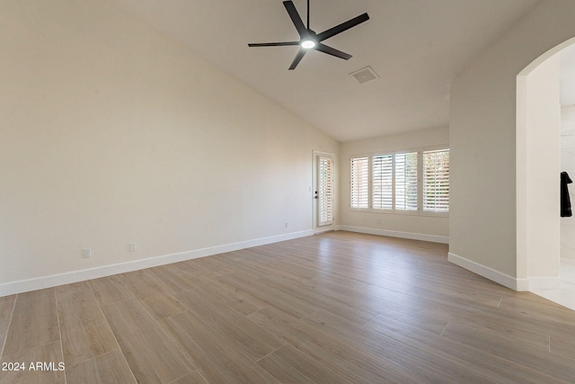 unfurnished room featuring arched walkways, ceiling fan, wood finished floors, baseboards, and high vaulted ceiling