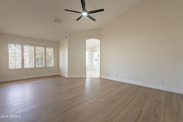 unfurnished room featuring lofted ceiling, arched walkways, ceiling fan, wood finished floors, and baseboards