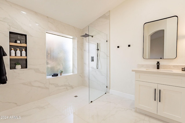 bathroom featuring marble tiled floors, a marble finish shower, vanity, and baseboards