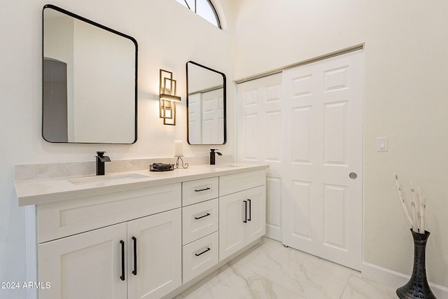 full bath with marble finish floors, double vanity, and baseboards