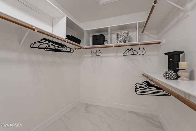 walk in closet with light marble finish floors