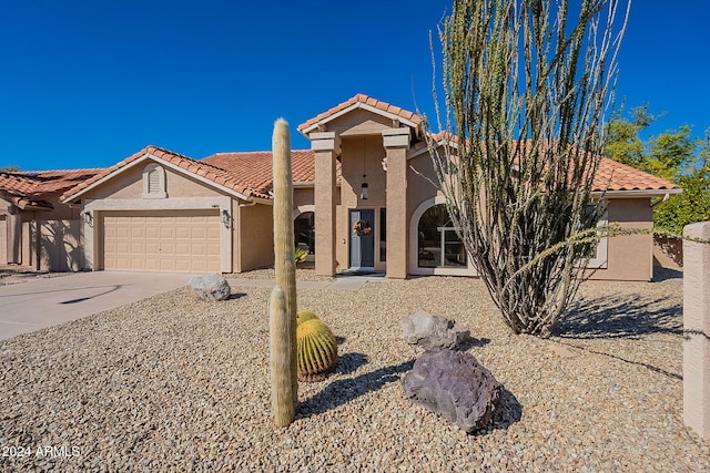 mediterranean / spanish-style house featuring stucco siding, a tiled roof, an attached garage, and concrete driveway
