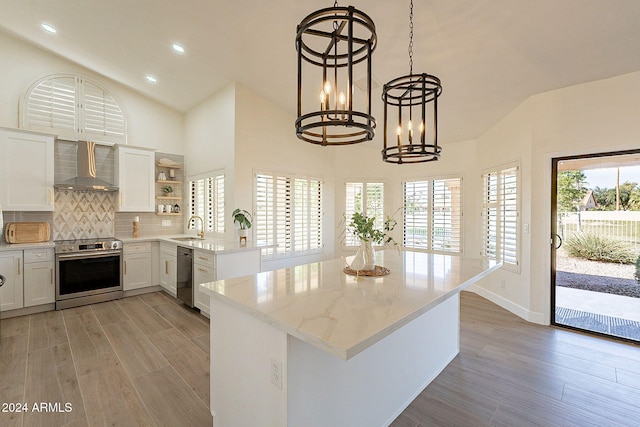 kitchen featuring stainless steel appliances, sink, light hardwood / wood-style flooring, white cabinets, and wall chimney range hood