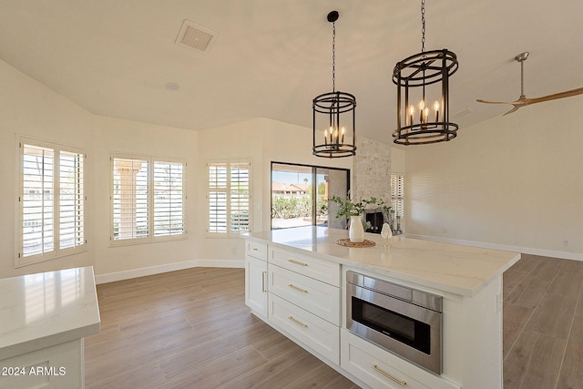 kitchen featuring white cabinets, a healthy amount of sunlight, light hardwood / wood-style flooring, and light stone counters