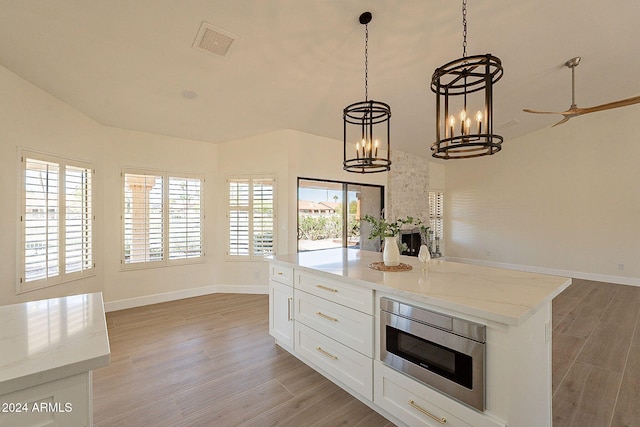 kitchen featuring light wood-style flooring, open floor plan, a chandelier, and baseboards