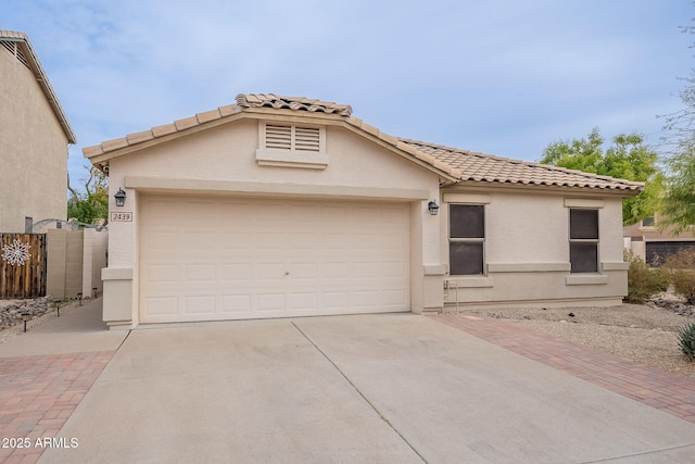 view of front of home featuring concrete driveway, a tiled roof, an attached garage, fence, and stucco siding