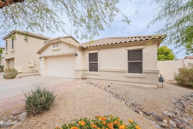 mediterranean / spanish home featuring driveway, fence, an attached garage, and stucco siding