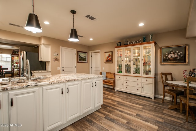 kitchen with white cabinetry, sink, pendant lighting, and light stone counters