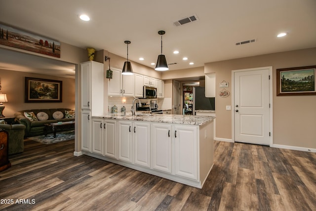 kitchen with decorative light fixtures, kitchen peninsula, stainless steel appliances, light stone countertops, and white cabinets