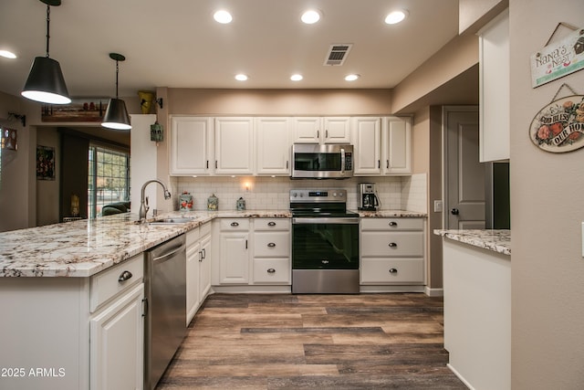 kitchen featuring sink, white cabinetry, kitchen peninsula, pendant lighting, and stainless steel appliances