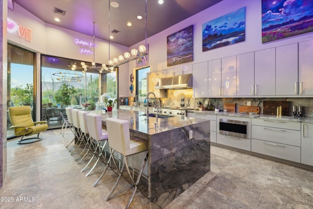 7846 E Wilderness Trl, Gold Canyon, AZ 85118 - kitchen featuring a sink, under cabinet range hood, modern cabinets, a towering ceiling, and light stone counters