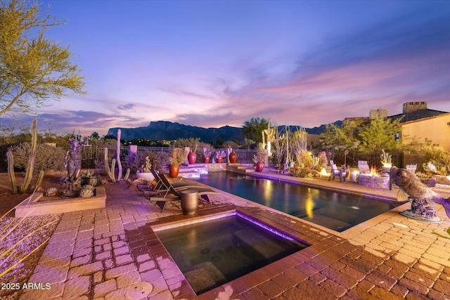 7846 E Wilderness Trl, Gold Canyon, AZ 85118 - pool at dusk featuring a mountain view, an in-ground hot tub, an outdoor fire pit, and a patio