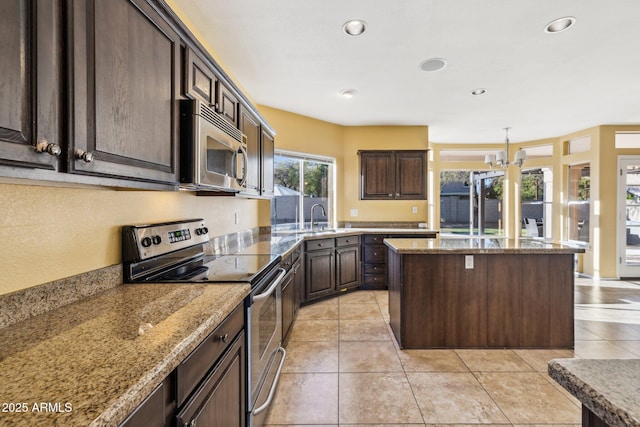 kitchen featuring dark brown cabinetry, light tile patterned flooring, appliances with stainless steel finishes, and a kitchen island