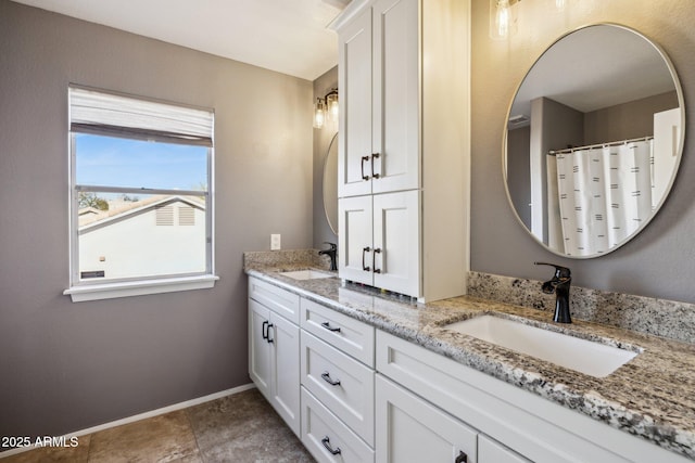 bathroom with double vanity, tile patterned flooring, baseboards, and a sink