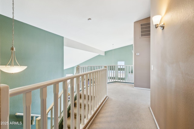 hallway featuring baseboards, visible vents, carpet floors, and lofted ceiling