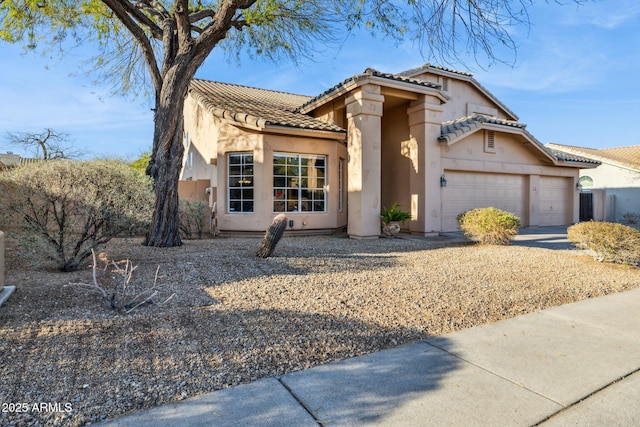 mediterranean / spanish house featuring stucco siding, driveway, an attached garage, and a tiled roof