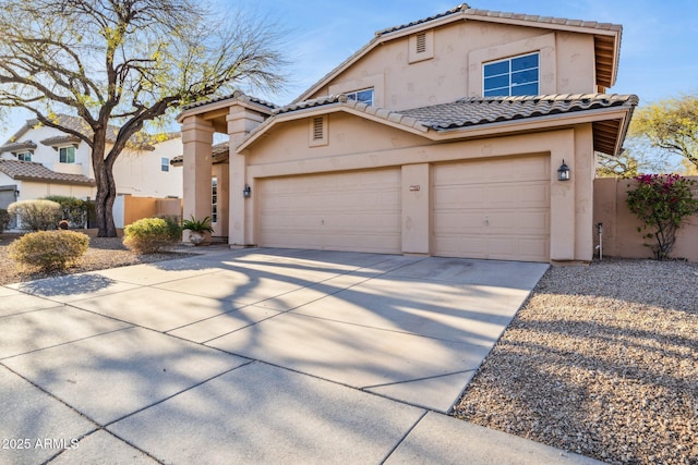 view of front of house featuring fence, a tiled roof, concrete driveway, stucco siding, and a garage