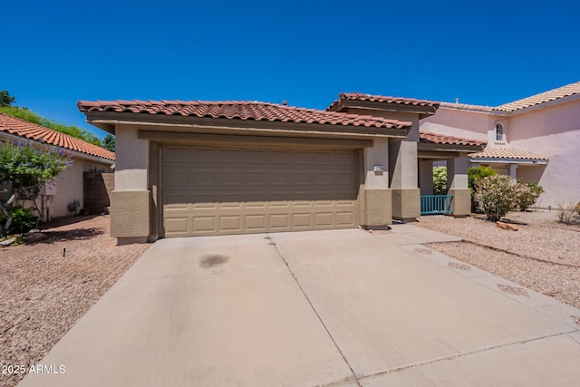 mediterranean / spanish house with driveway, stucco siding, an attached garage, and a tiled roof