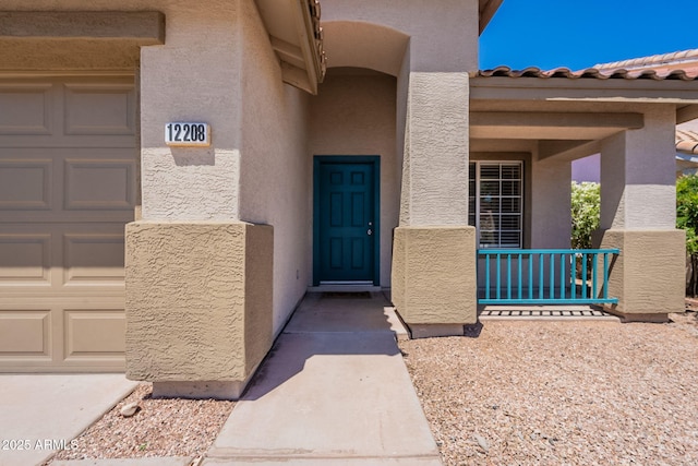 property entrance with covered porch, stucco siding, and a garage