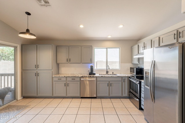 kitchen featuring appliances with stainless steel finishes, a sink, gray cabinetry, healthy amount of natural light, and recessed lighting