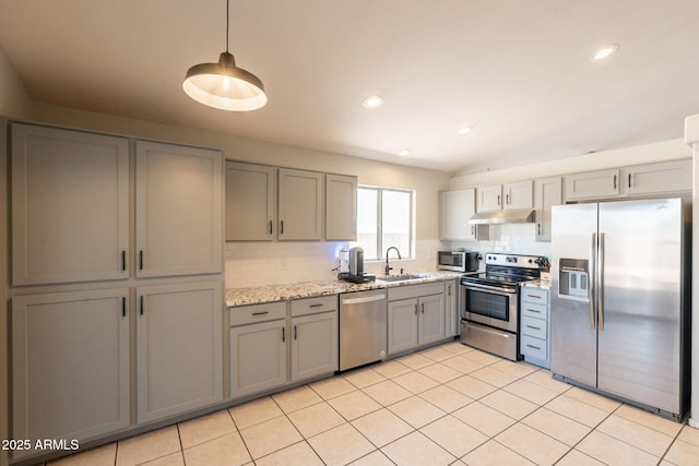 kitchen with appliances with stainless steel finishes, gray cabinetry, under cabinet range hood, a sink, and tasteful backsplash