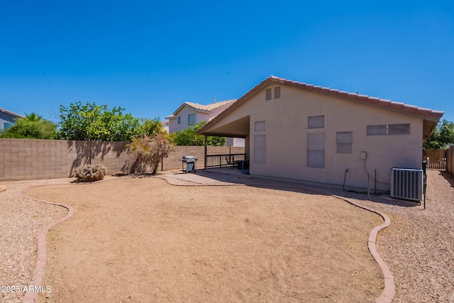 back of house with a tile roof, a fenced backyard, stucco siding, a patio area, and central AC