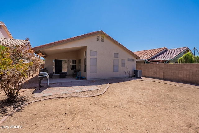 rear view of house with a patio area, a tiled roof, stucco siding, central air condition unit, and a fenced backyard