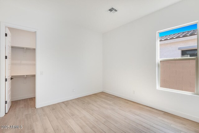 16994 W Canterbury Dr, Surprise, AZ 85388 - unfurnished bedroom featuring wood finished floors, a walk in closet, and baseboards