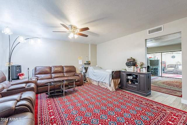 living room with ceiling fan, light hardwood / wood-style flooring, and a textured ceiling