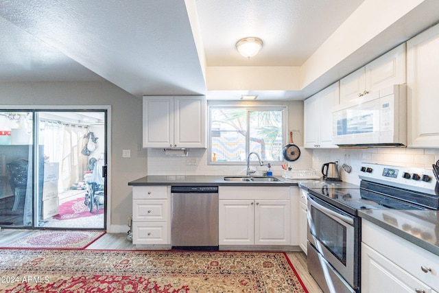 kitchen featuring white cabinets, sink, light hardwood / wood-style flooring, stainless steel appliances, and decorative backsplash