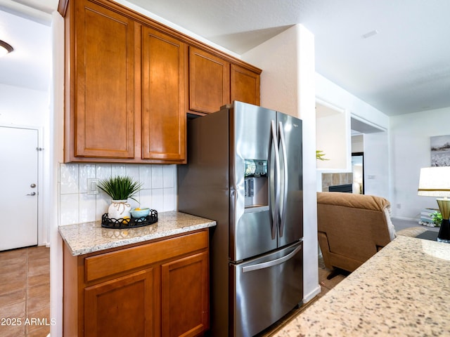 19403 E Arrowhead Trl, Queen Creek, AZ 85142 - kitchen featuring stainless steel fridge with ice dispenser, tasteful backsplash, brown cabinets, light stone countertops, and open floor plan
