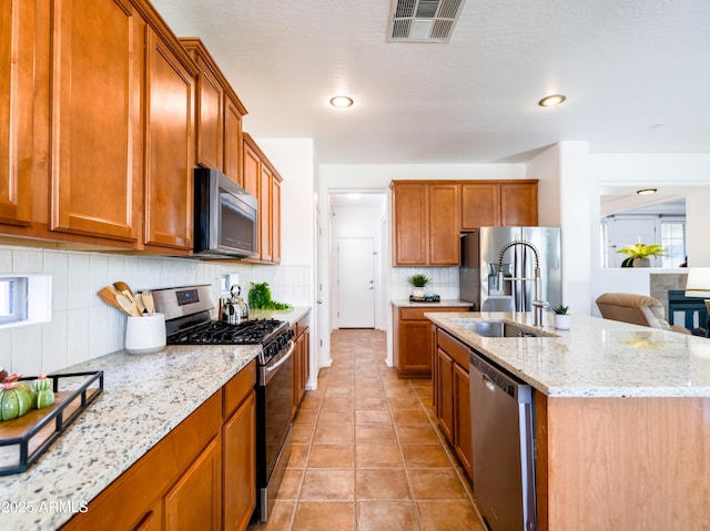 19403 E Arrowhead Trl, Queen Creek, AZ 85142 - kitchen featuring appliances with stainless steel finishes, a sink, brown cabinetry, backsplash, and a center island with sink