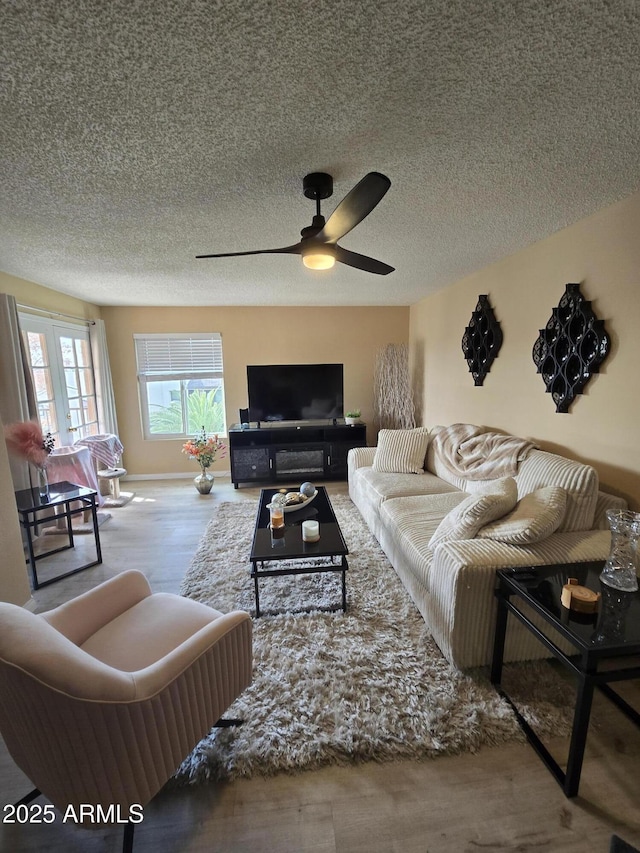 living room featuring a textured ceiling, ceiling fan, and light hardwood / wood-style floors