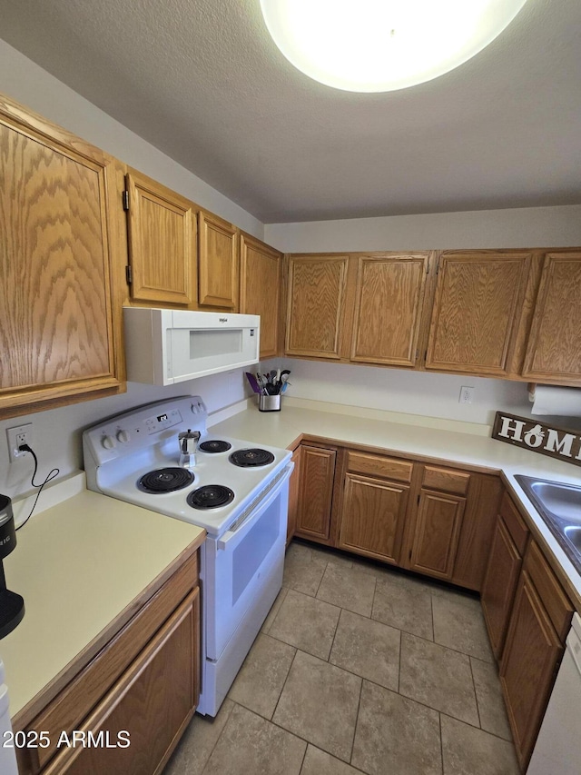 kitchen with white appliances, light tile patterned floors, and a textured ceiling