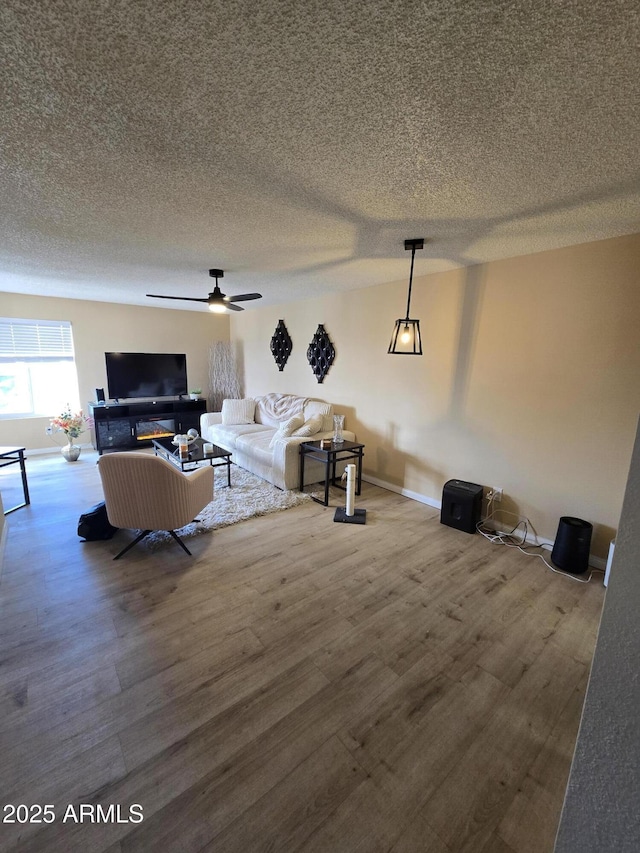 living room with a textured ceiling, ceiling fan, and wood-type flooring