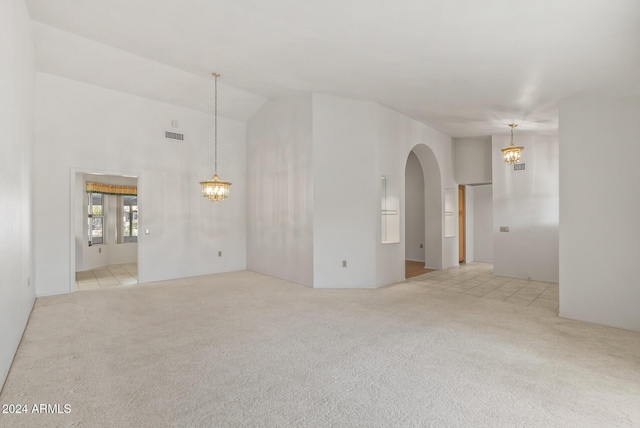 carpeted spare room featuring an inviting chandelier and vaulted ceiling